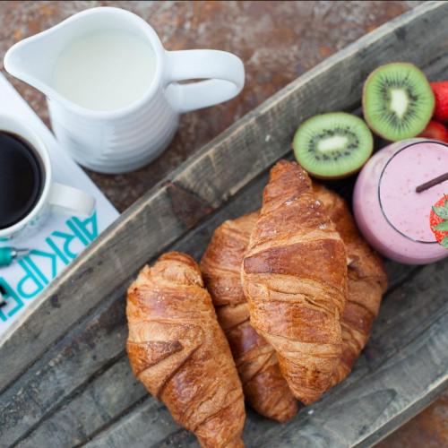 Konferensblock och penna med kaffe, frukt, smoothie och croissanter.