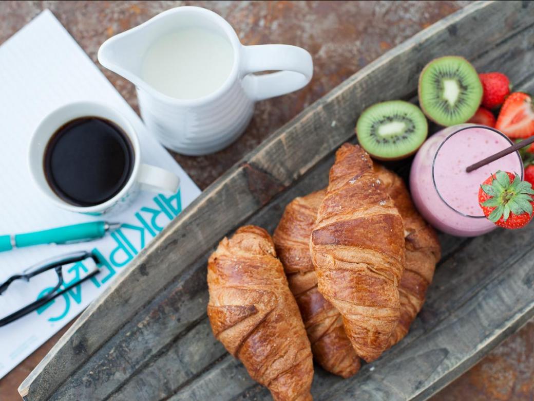 Konferensblock och penna med kaffe, frukt, smoothie och croissanter.